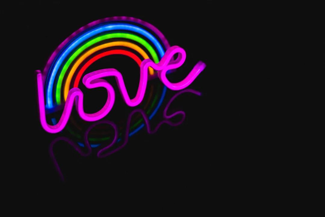 Illustration of illuminated multicolored neon rainbow with love text against black background - Image