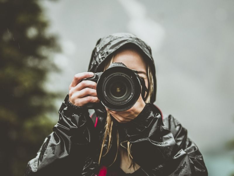 A female photographer pointing her digital camera towards the viewer - Keep posting and updating your Instagram stories - Image